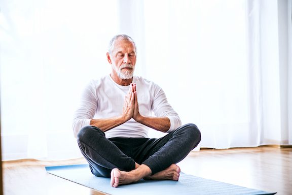 Older man sitting in a yoga pose.