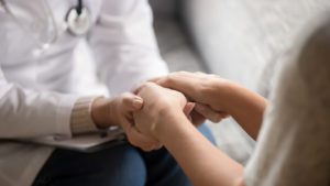 Close up horizontal image doctor holding hands of female patient